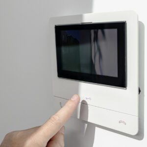 Intercom in home interior and a hand ready to open the door button. House Security system. Copy space